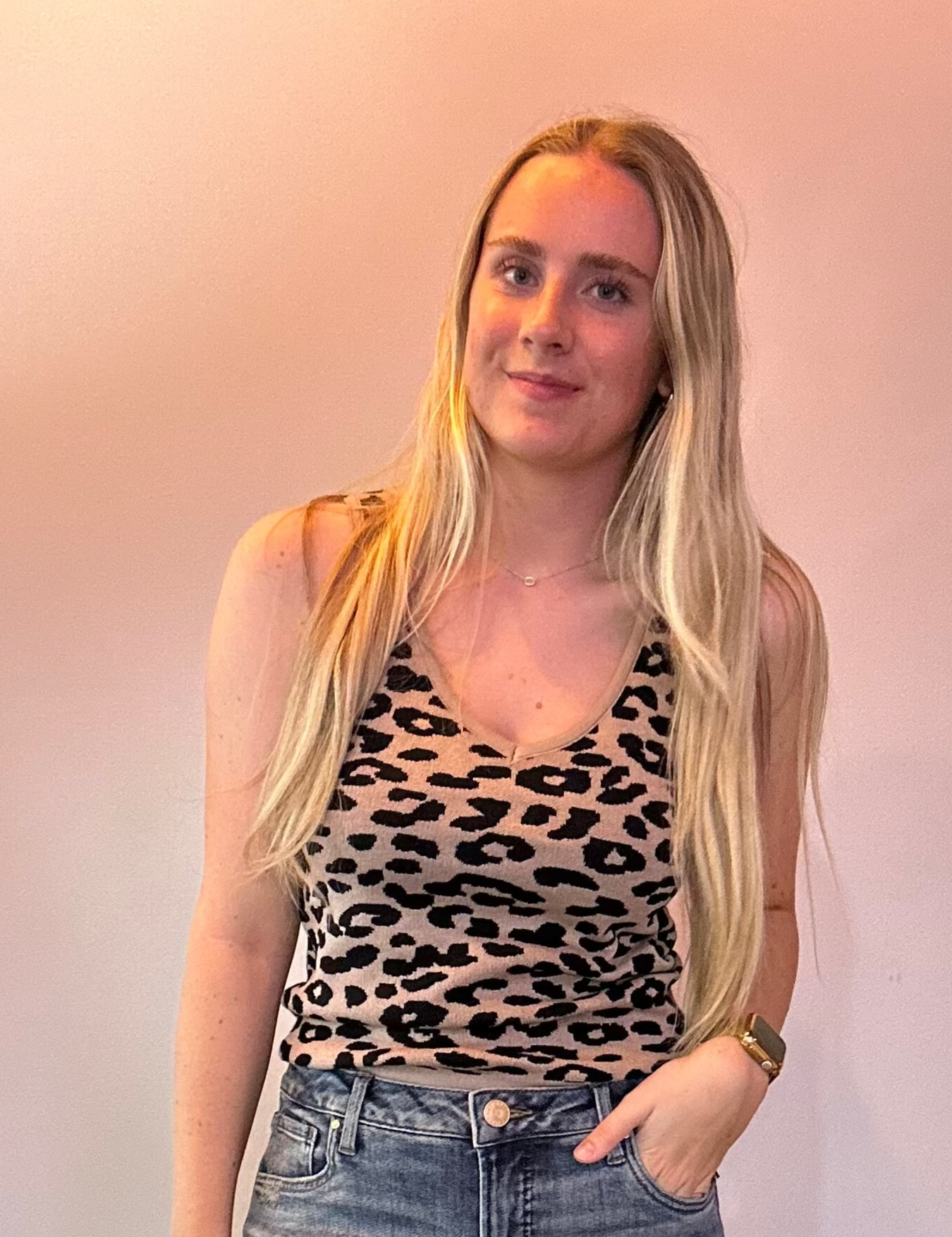 Woman wearing a leopard print top and blue jeans against a plain background