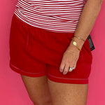 Woman wearing red linen blend tie front shorts with a lattice trim hem and a white tank top