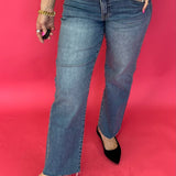 Woman wearing medium wash high rise straight leg jeans with a roomy fit and a raw hem
