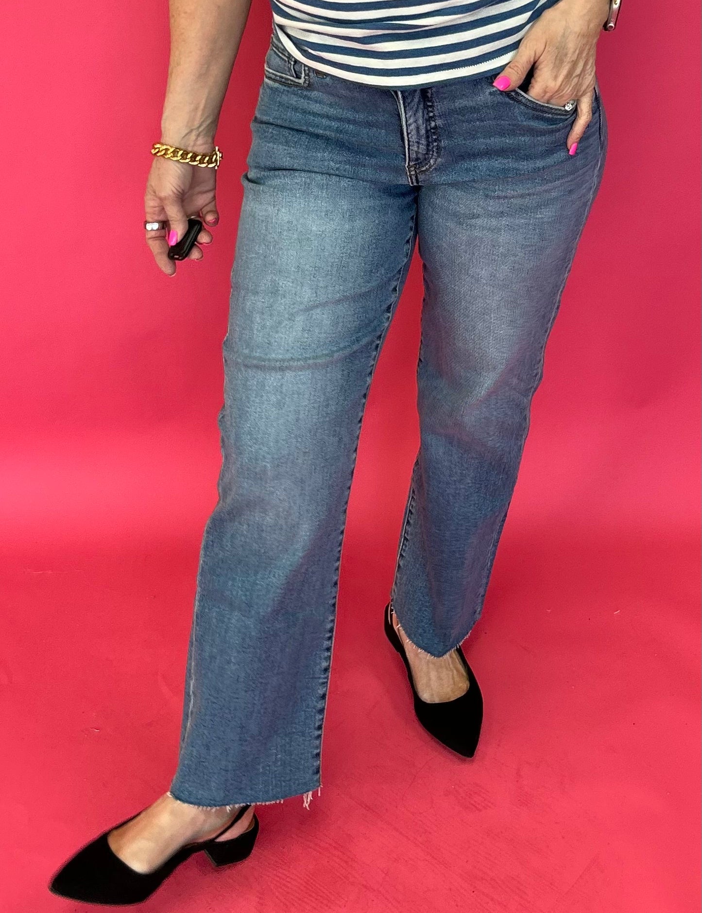 Woman wearing medium wash high rise straight leg jeans with a roomy fit and a raw hem