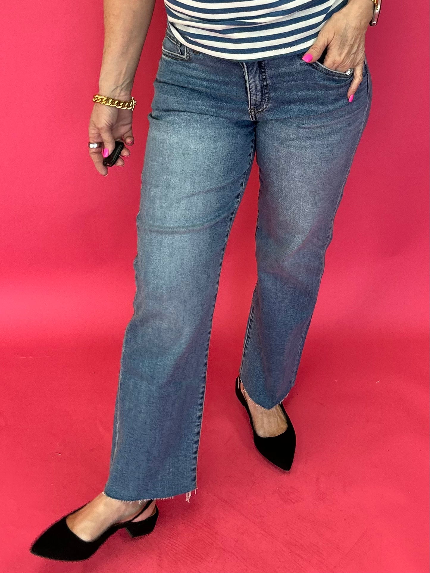 Woman wearing medium wash high rise straight leg jeans with a roomy fit and a raw hem