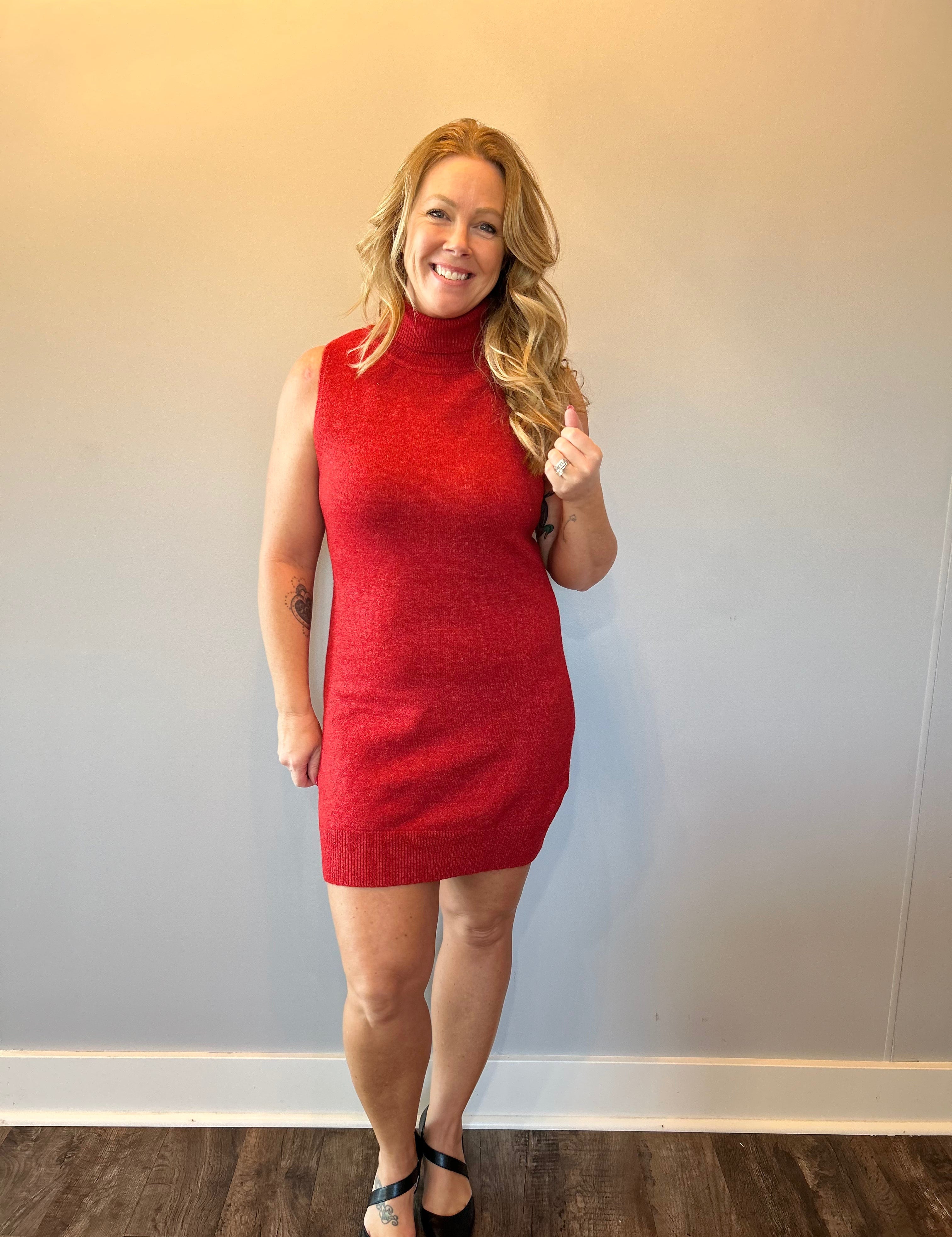 Woman wearing a red ribbed knit sleeveless midi sweater dress with a crew neckline and tall boots