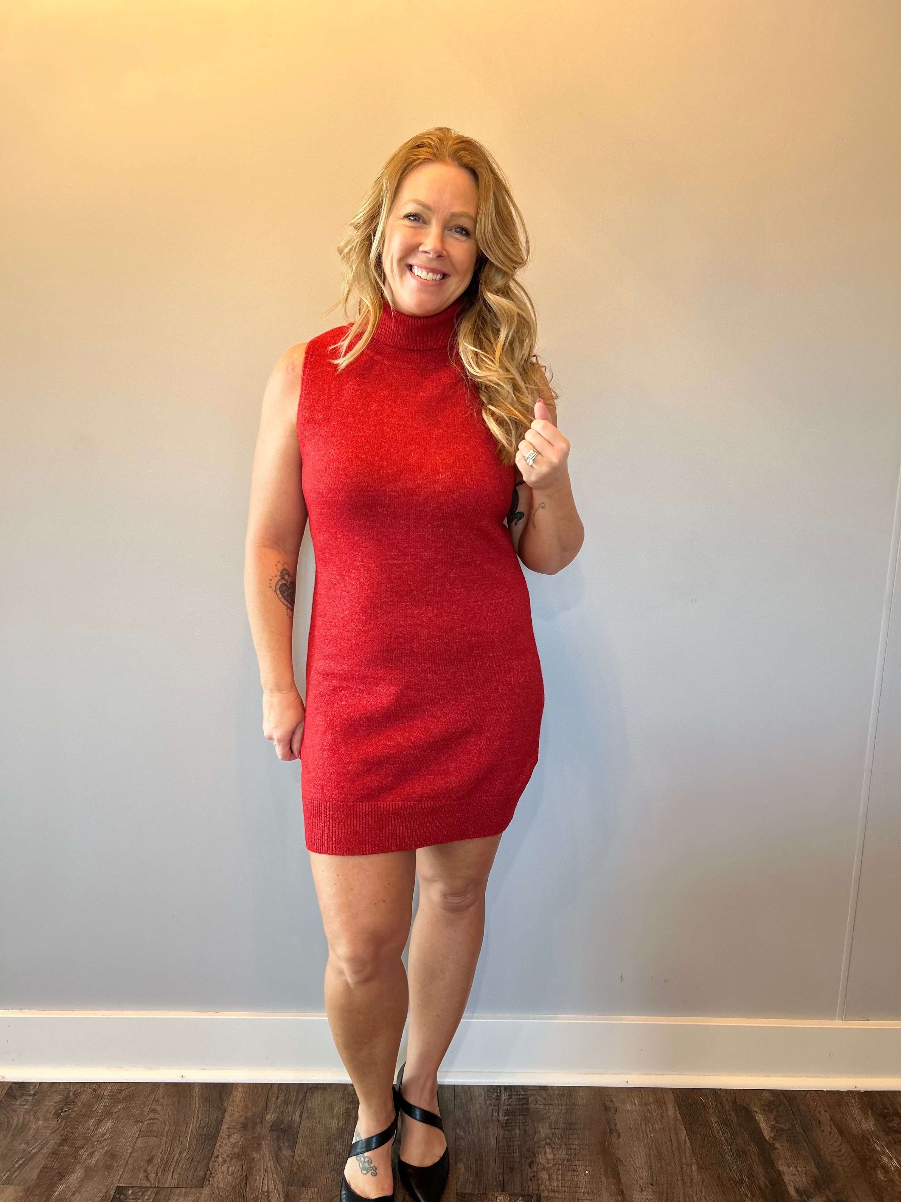 Woman wearing a red ribbed knit sleeveless midi sweater dress with a crew neckline and tall boots