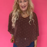 Woman wearing a sheer brown polka dot mesh poncho with a wide boat neck layered over a tank and trousers