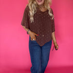 Close-up of the sheer polka dot mesh fabric and wide boat neckline on the brown poncho
