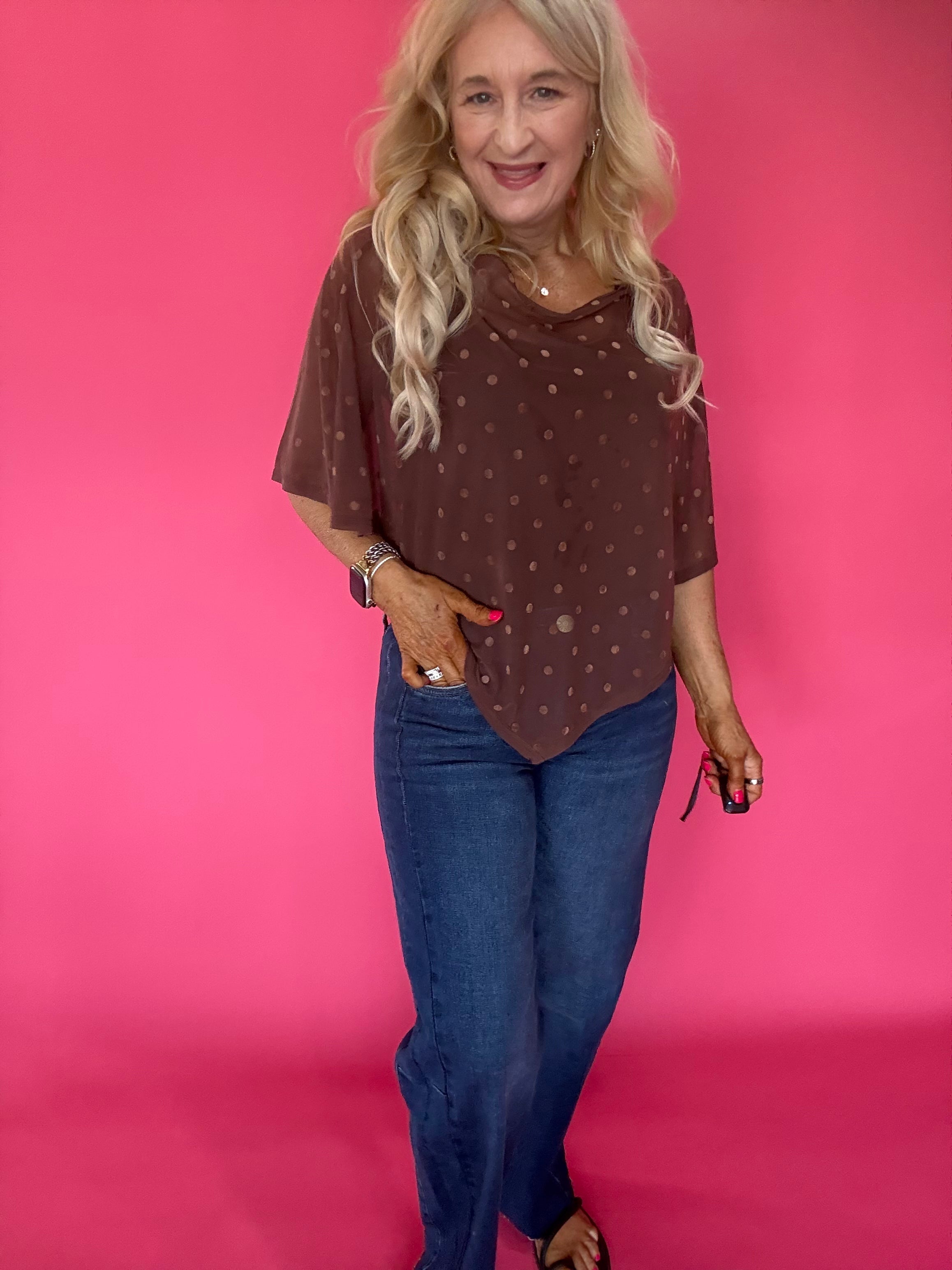 Close-up of the sheer polka dot mesh fabric and wide boat neckline on the brown poncho