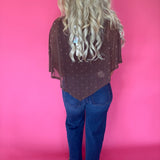 Detail of the brown polka dot mesh layered over a fitted top and high-waisted trousers
