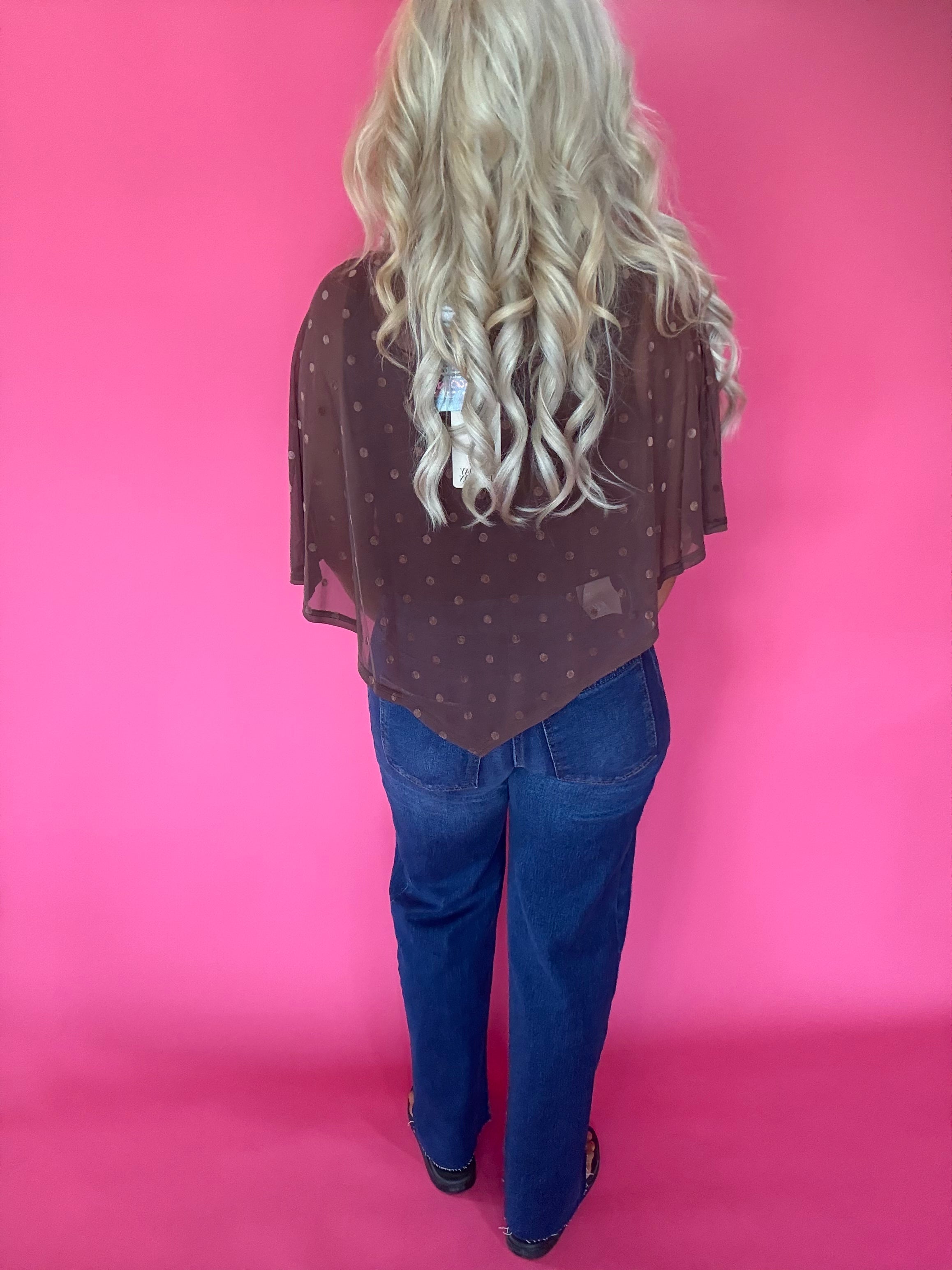 Detail of the brown polka dot mesh layered over a fitted top and high-waisted trousers