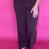 Woman wearing soft brown everyday trousers with a tucked blouse and low heels for work