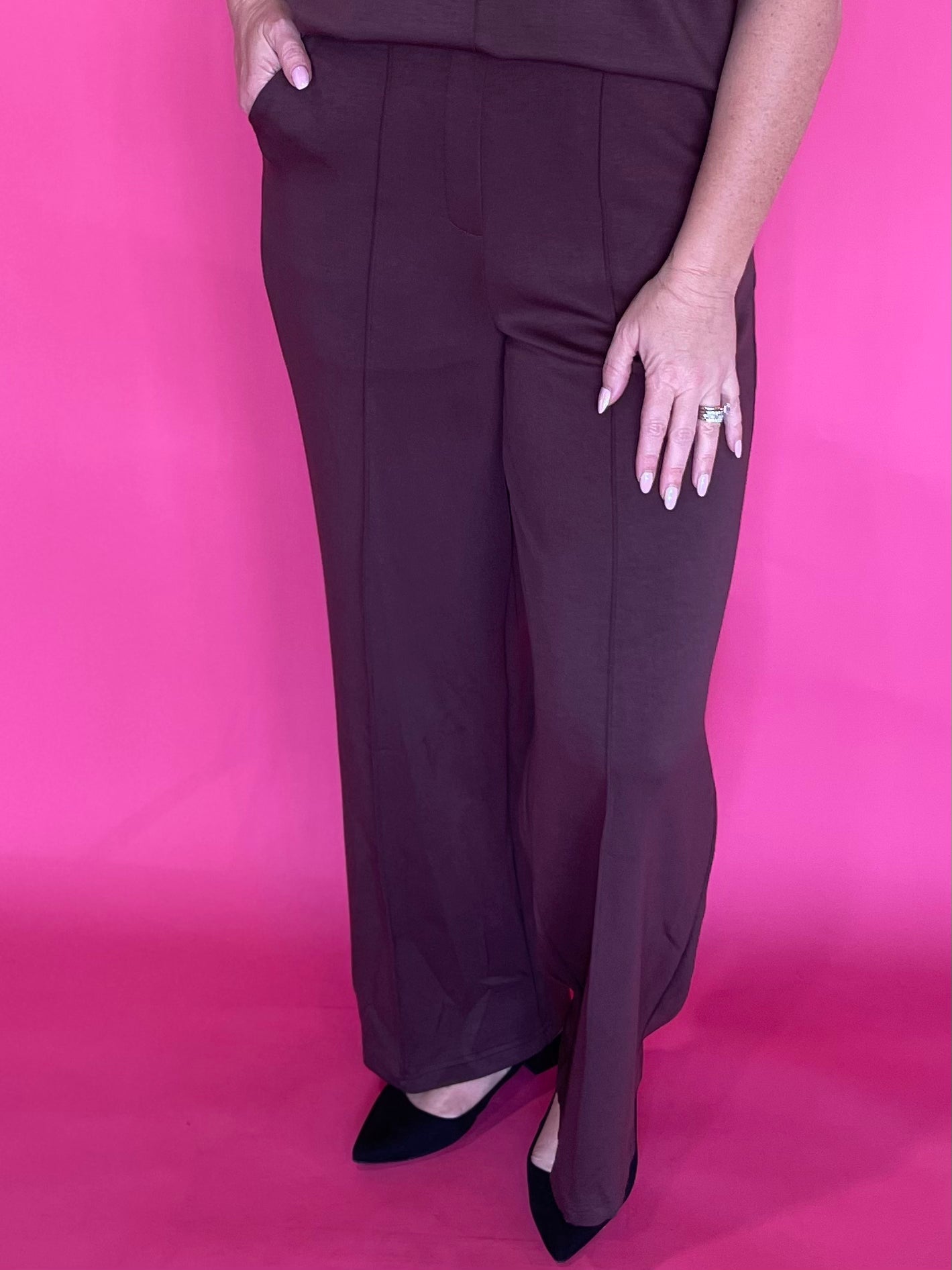 Woman wearing soft brown everyday trousers with a tucked blouse and low heels for work