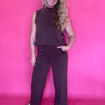 Close-up of the smooth brown woven fabric and stitched seam detail on the trousers