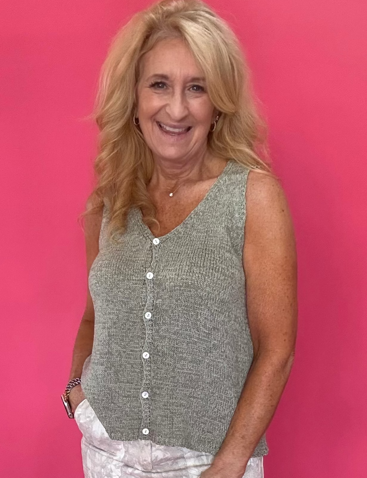 Woman wearing a sage green button front sweater vest with a V-neckline and relaxed fit