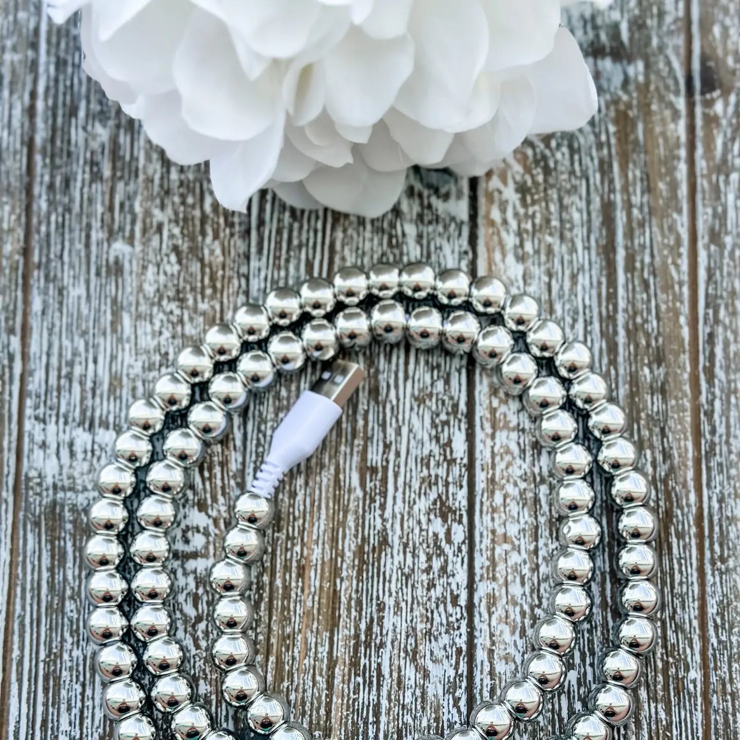 Gold pearl beaded 2 in 1 phone charging cable coiled beside a phone with iPhone and USB-C tips