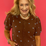 Woman wearing a cocoa brown polka dot cardigan styled open over a simple top with denim