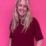 Woman wearing a burgundy soft knit pullover sweater with a relaxed fit and ribbed crew neck