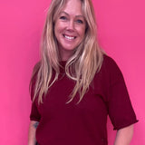 Woman wearing a burgundy soft knit pullover sweater with a relaxed fit and ribbed crew neck