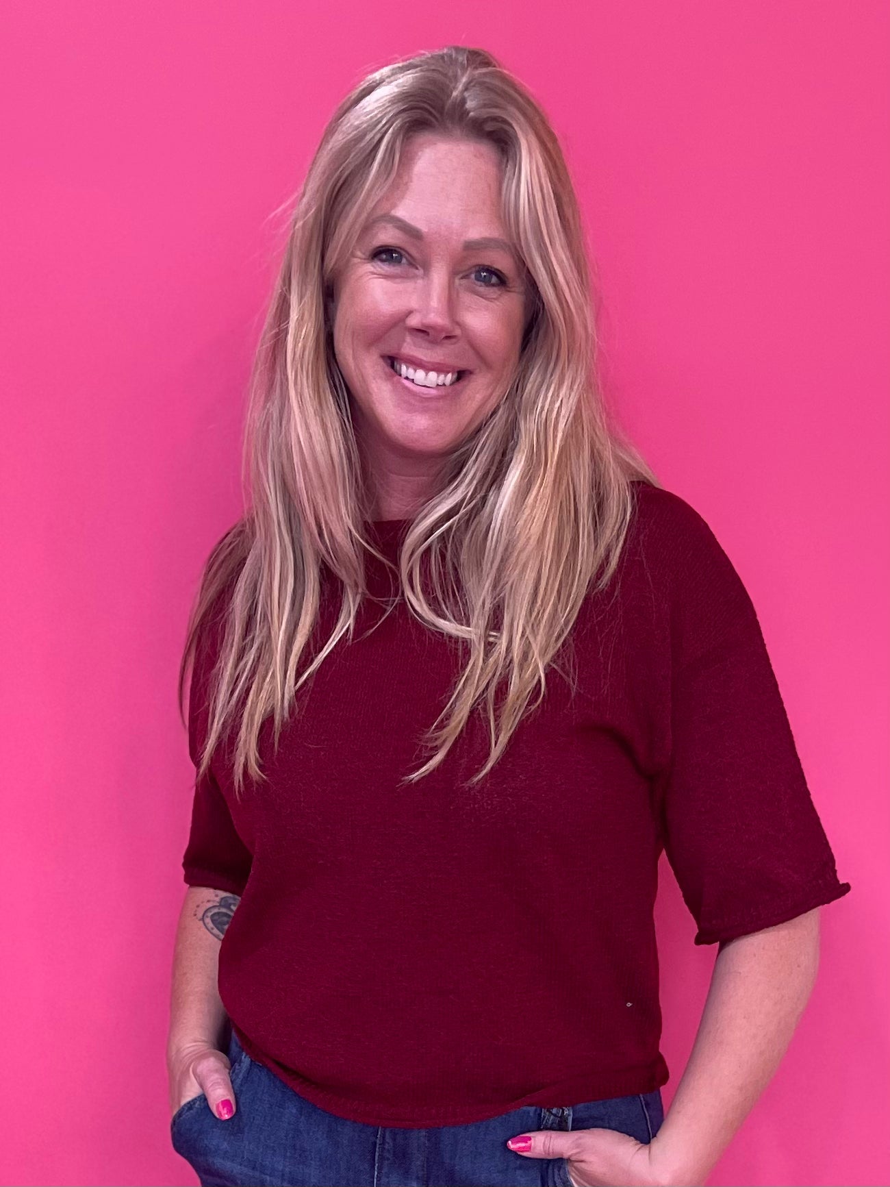 Woman wearing a burgundy soft knit pullover sweater with a relaxed fit and ribbed crew neck