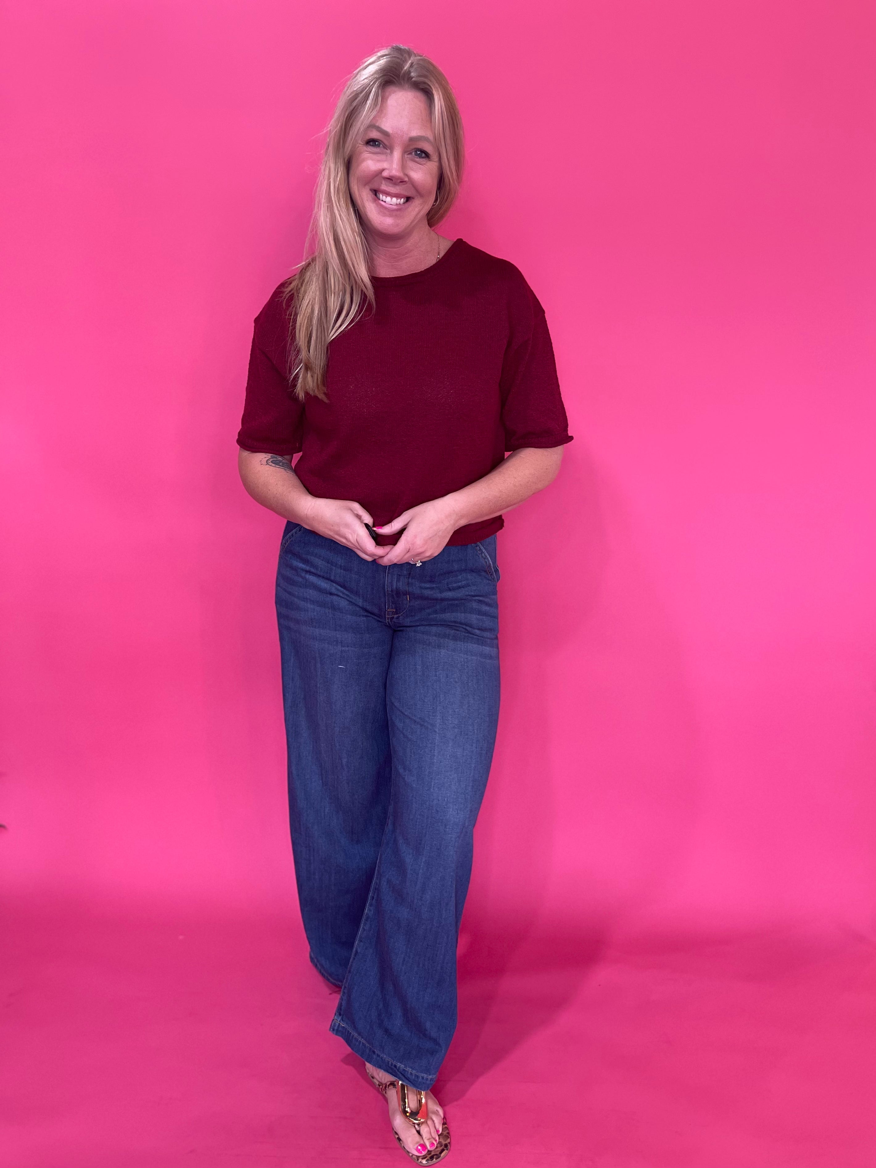 Side view of the burgundy pullover sweater worn with tailored trousers for the office