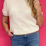 Woman wearing an oatmeal soft knit pullover sweater with a relaxed fit, styled with blue denim jeans