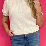 Woman wearing an oatmeal soft knit pullover sweater with a relaxed fit, styled with blue denim jeans