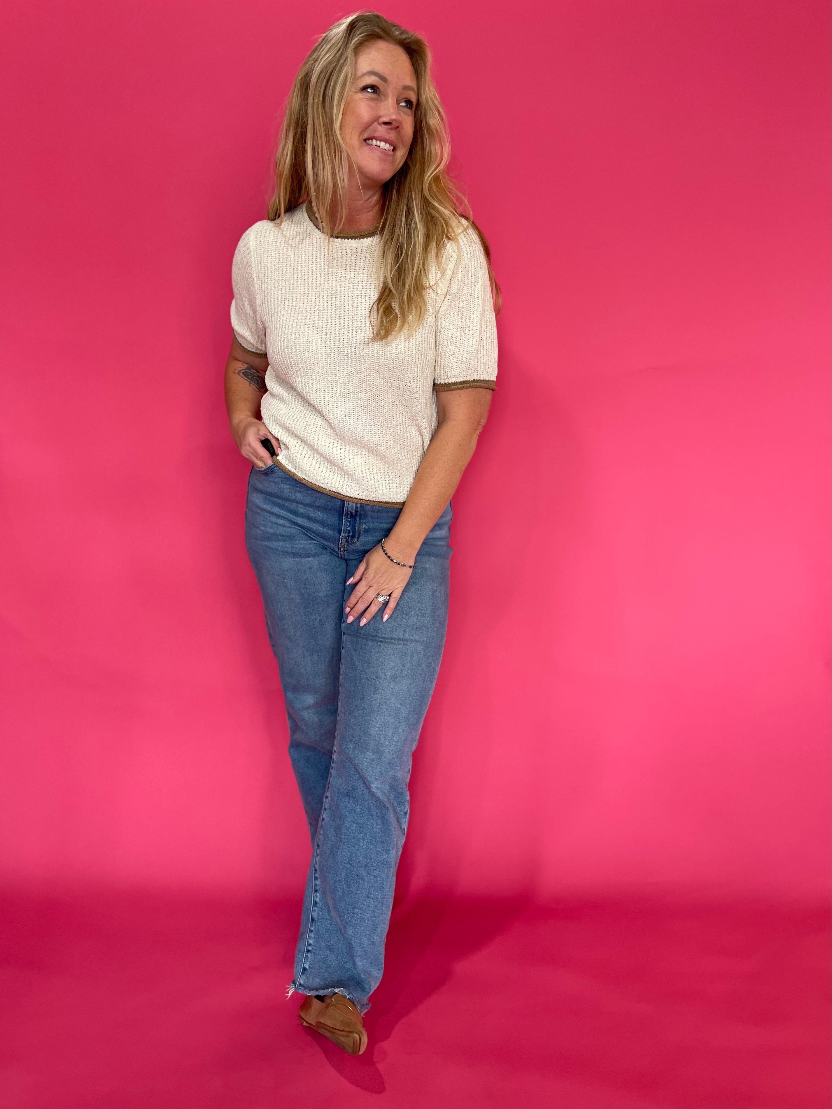 Side view of the oatmeal pullover sweater showing the hip length hem worn over high rise denim