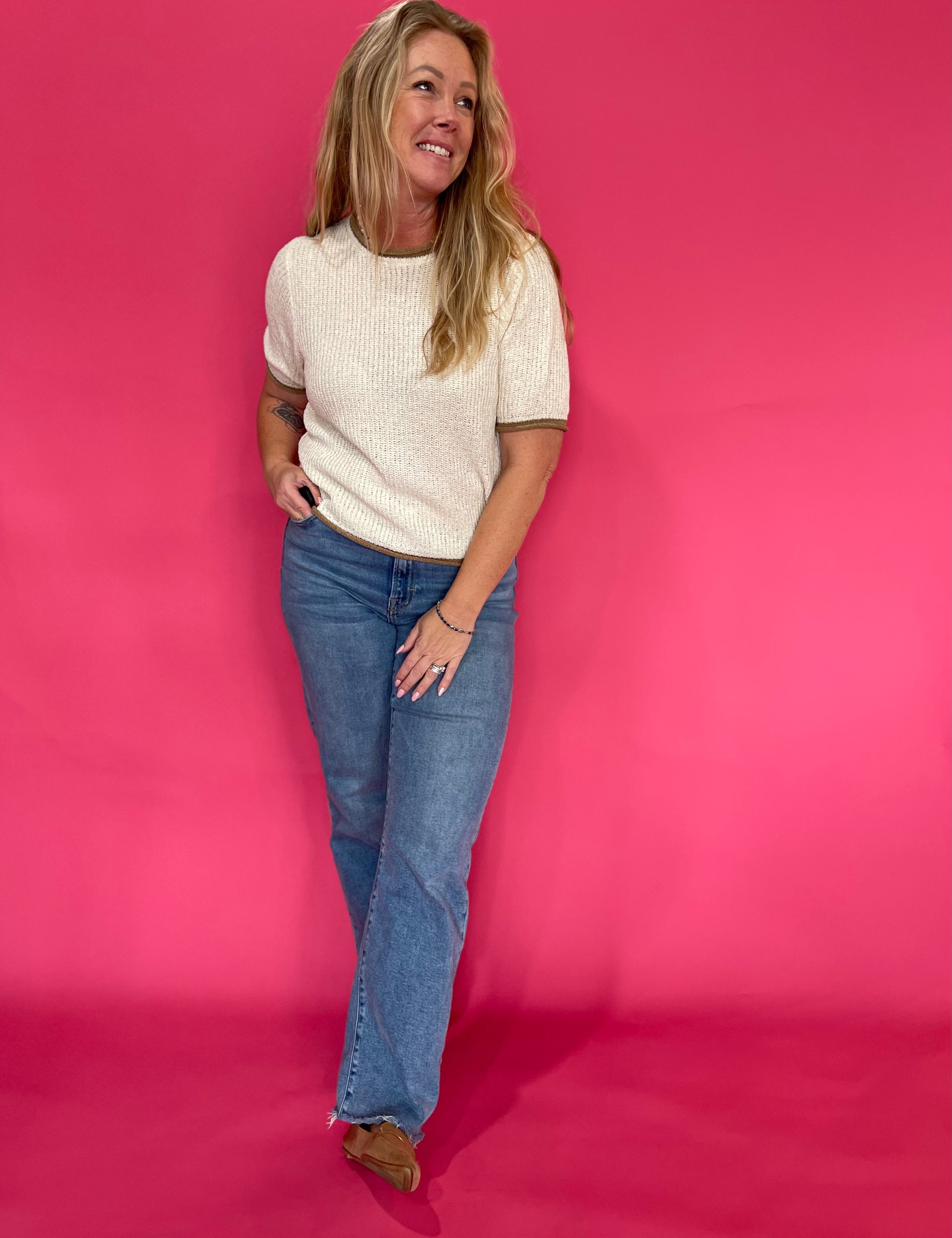Side view of the oatmeal pullover sweater showing the hip length hem worn over high rise denim