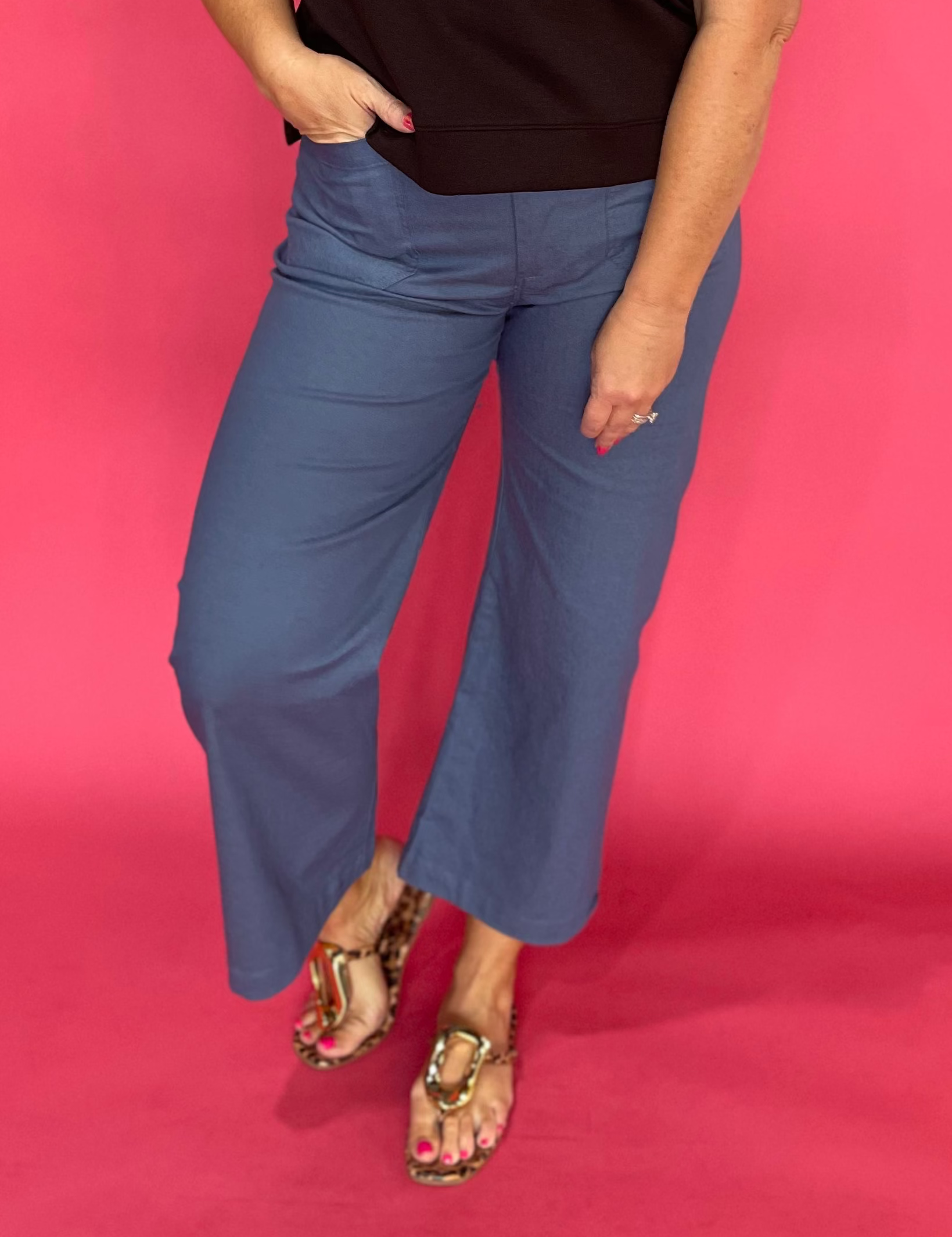 Woman wearing grey high rise cropped pants with front patch pockets and a wide straight leg