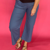 Woman wearing grey high rise cropped pants with front patch pockets and a wide straight leg