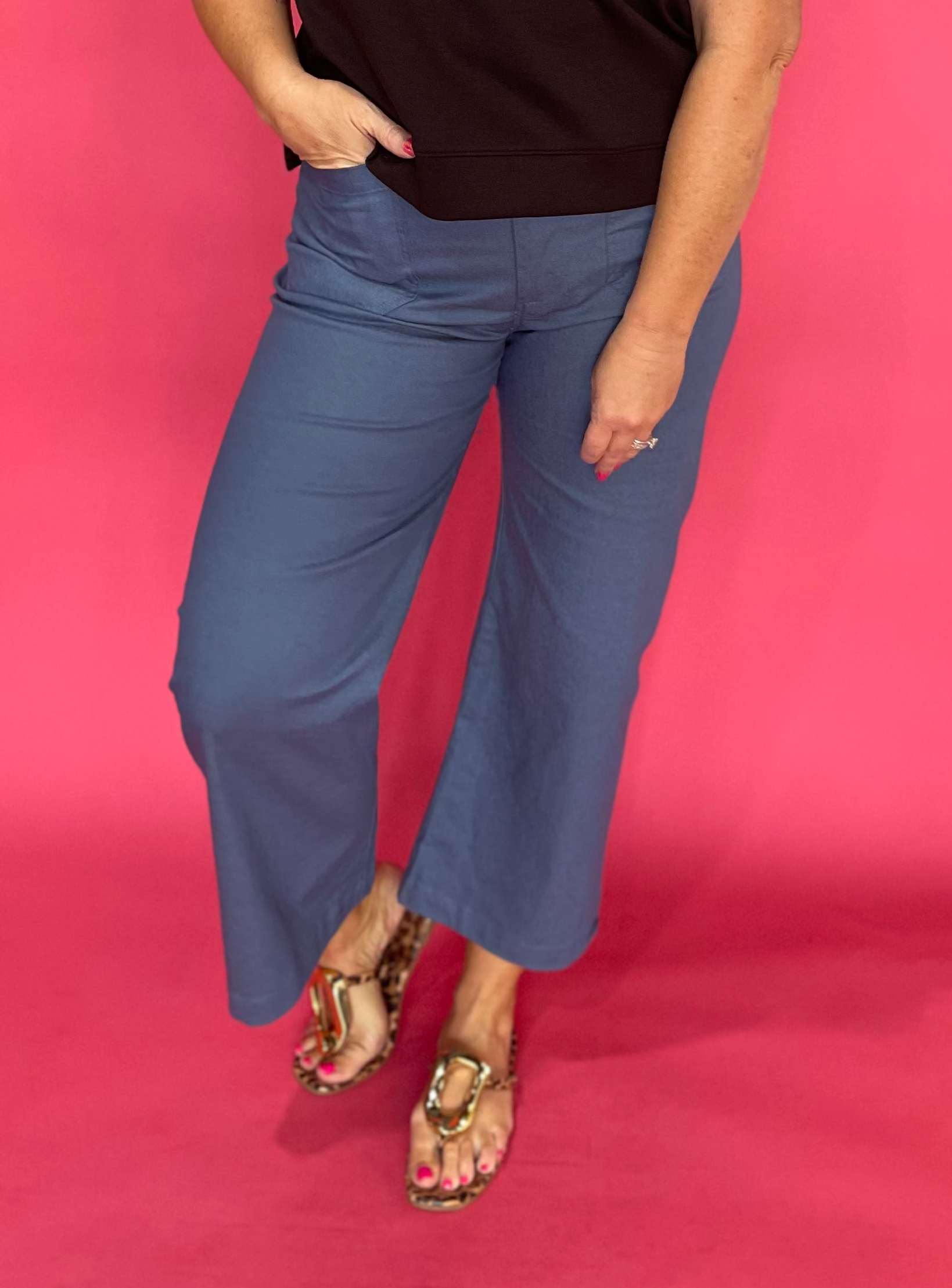 Woman wearing grey high rise cropped pants with front patch pockets and a wide straight leg