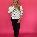 Close-up of the ruffle trim running down the deep V-neckline of the polka dot woven top