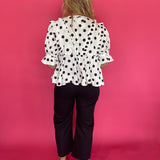 Detail of the black and white polka dot woven fabric and ruffle placket on the babydoll top