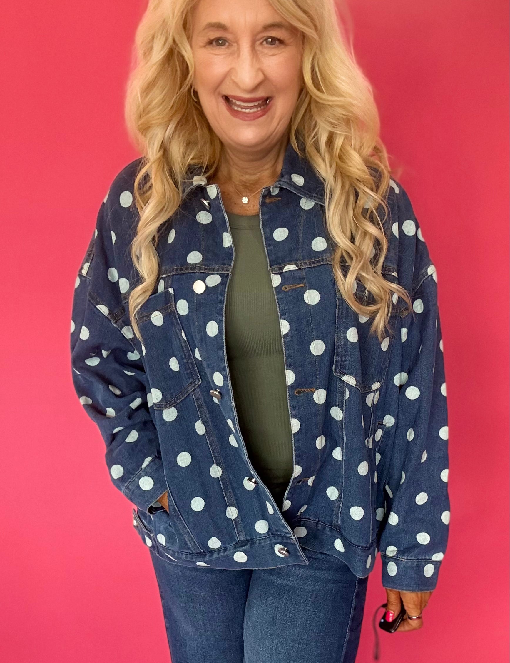 Woman wearing an oversized dark wash denim jacket with cream polka dots over a white tee and shorts