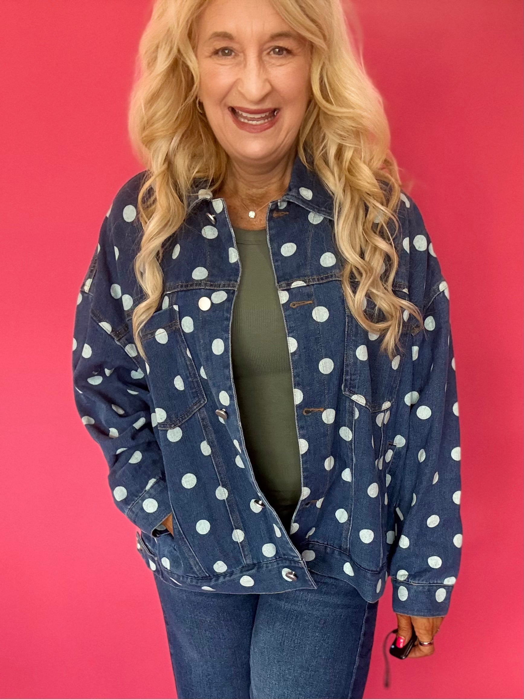 Woman wearing an oversized dark wash denim jacket with cream polka dots over a white tee and shorts