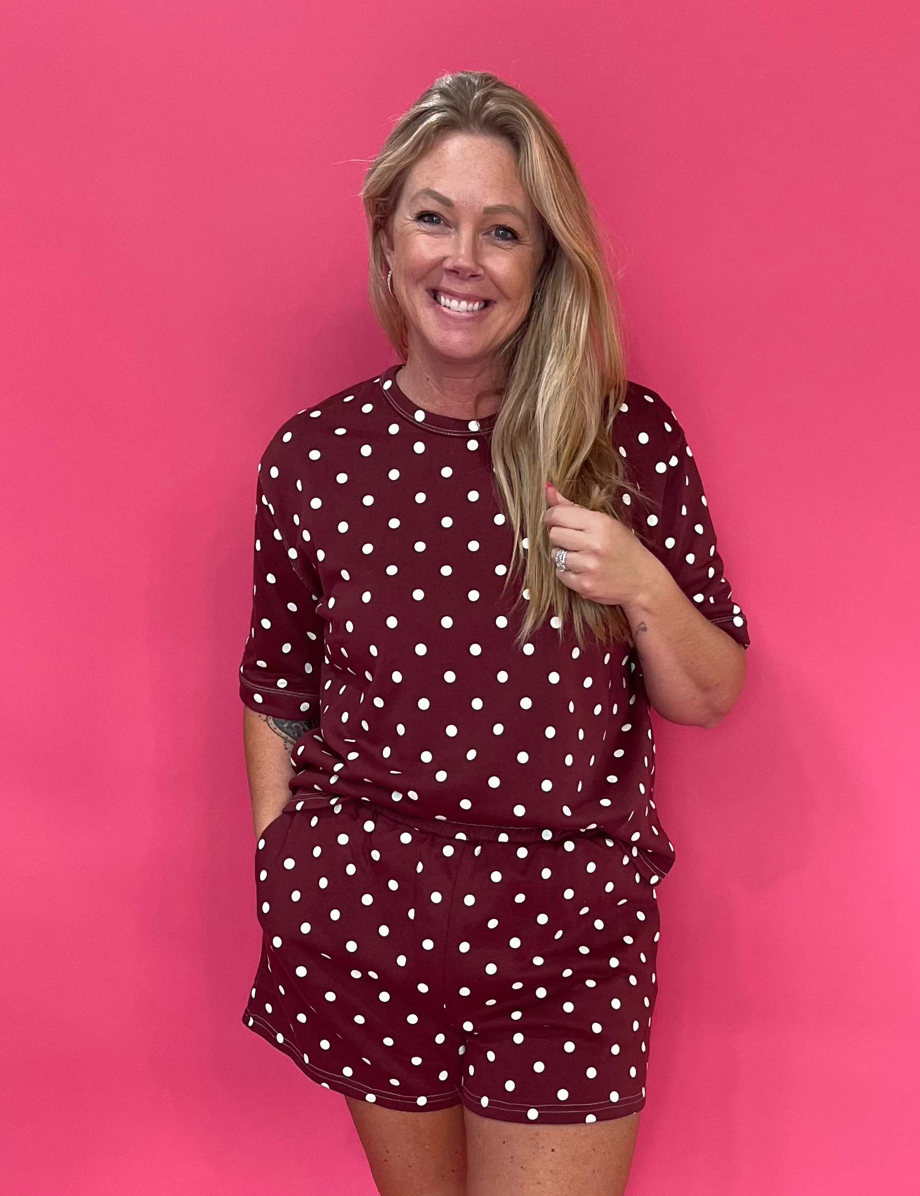 Woman wearing a wine polka dot short sleeve knit top with matching easy shorts and slide sandals