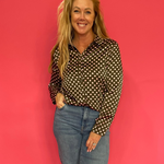 Woman wearing an olive polka dot satin button down shirt half tucked into high waist denim