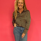 Woman wearing an olive polka dot satin button down shirt half tucked into high waist denim