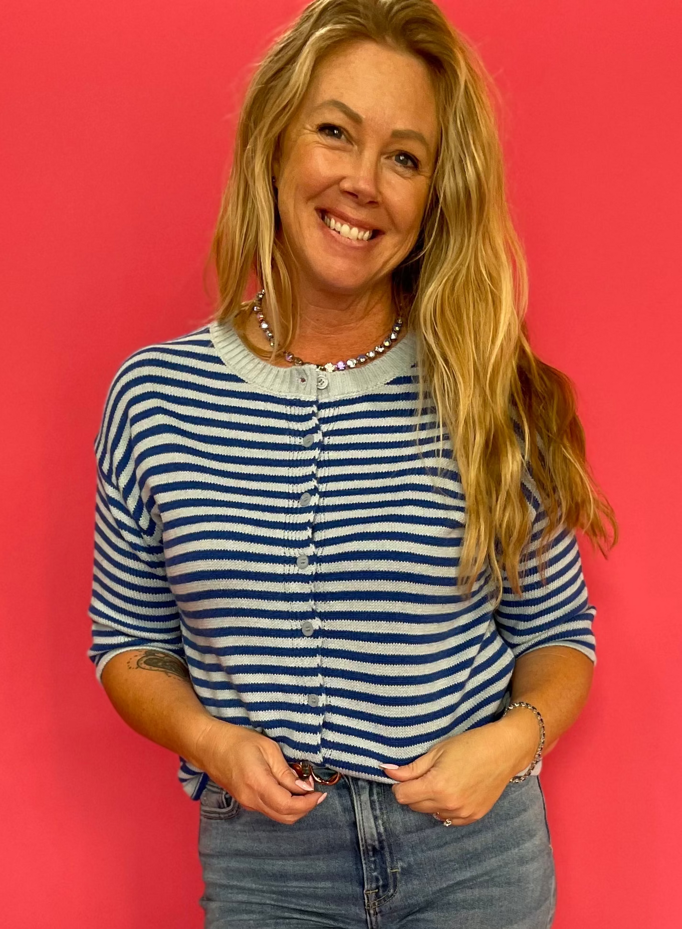 Woman wearing a blue and white striped fuzzy knit cropped cardigan with light blue contrast trim
