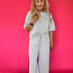 Side view of the lounge set showing the side pocket and wide leg hem with white sneakers