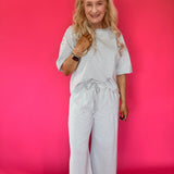 Side view of the lounge set showing the side pocket and wide leg hem with white sneakers