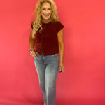 Full length view of the burgundy sleeveless knit cardigan layered over a cream tank and jeans