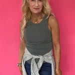 Woman wearing a green ribbed knit tank with a crew neckline tucked into high waisted denim
