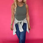 Detail of the crew neckline and finished hem on the fitted green ribbed knit tank