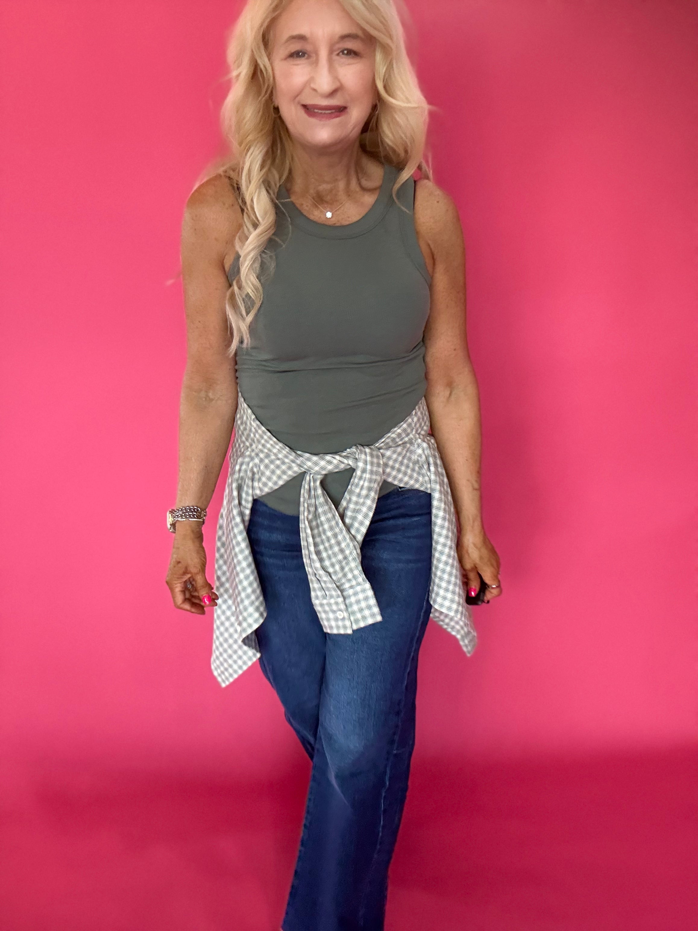 Detail of the crew neckline and finished hem on the fitted green ribbed knit tank