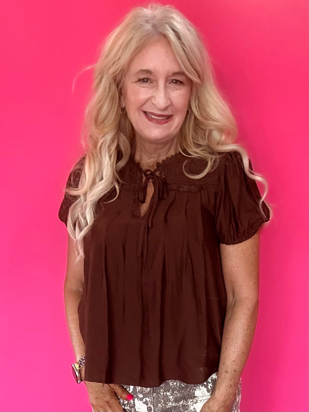 Woman wearing a lightweight brown woven blouse tucked into high waisted denim with an easy drape