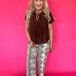 Back view of the brown woven blouse showing its relaxed everyday drape through the shoulders