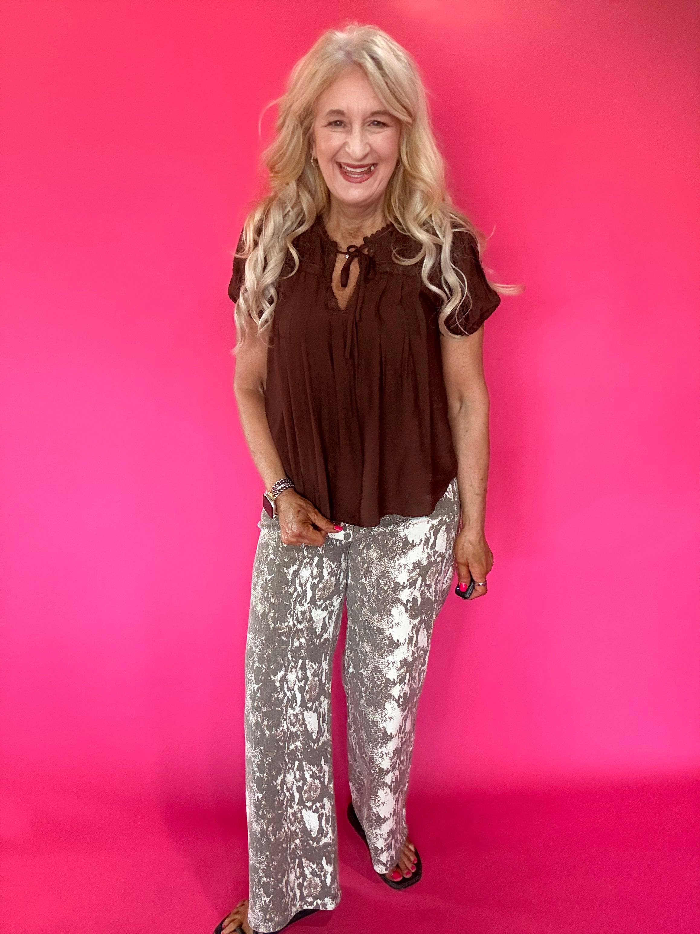 Back view of the brown woven blouse showing its relaxed everyday drape through the shoulders