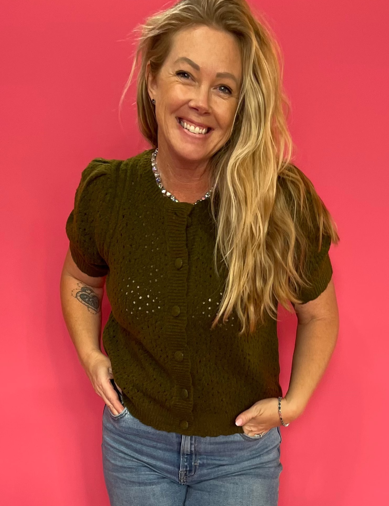 Woman wearing a soft olive boxy knit top tucked into high-waisted denim with sneakers