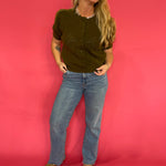 Detail of the soft olive knit fabric on the boxy top styled with wide leg pants and mules