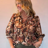 Woman wearing a floral print peplum blouse with a tie front closure and three-quarter sleeves