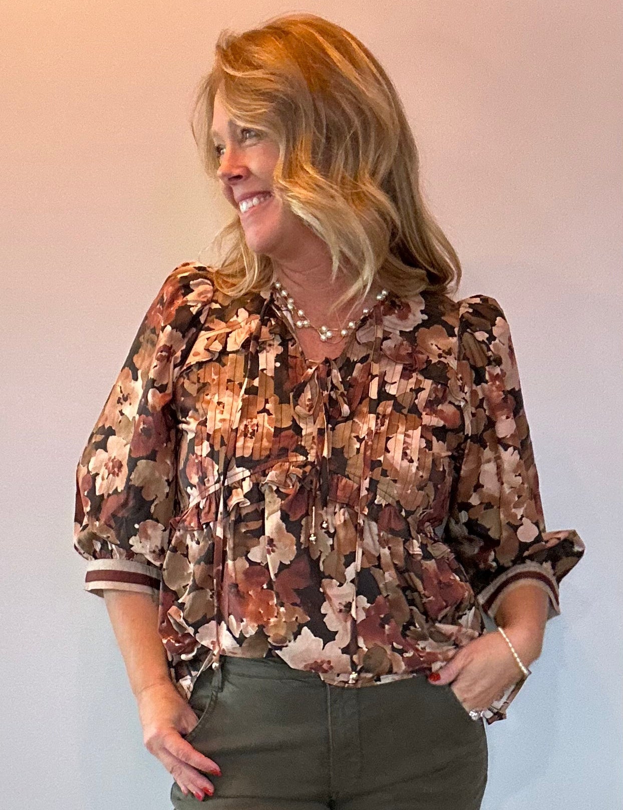 Woman wearing a floral print peplum blouse with a tie front closure and three-quarter sleeves